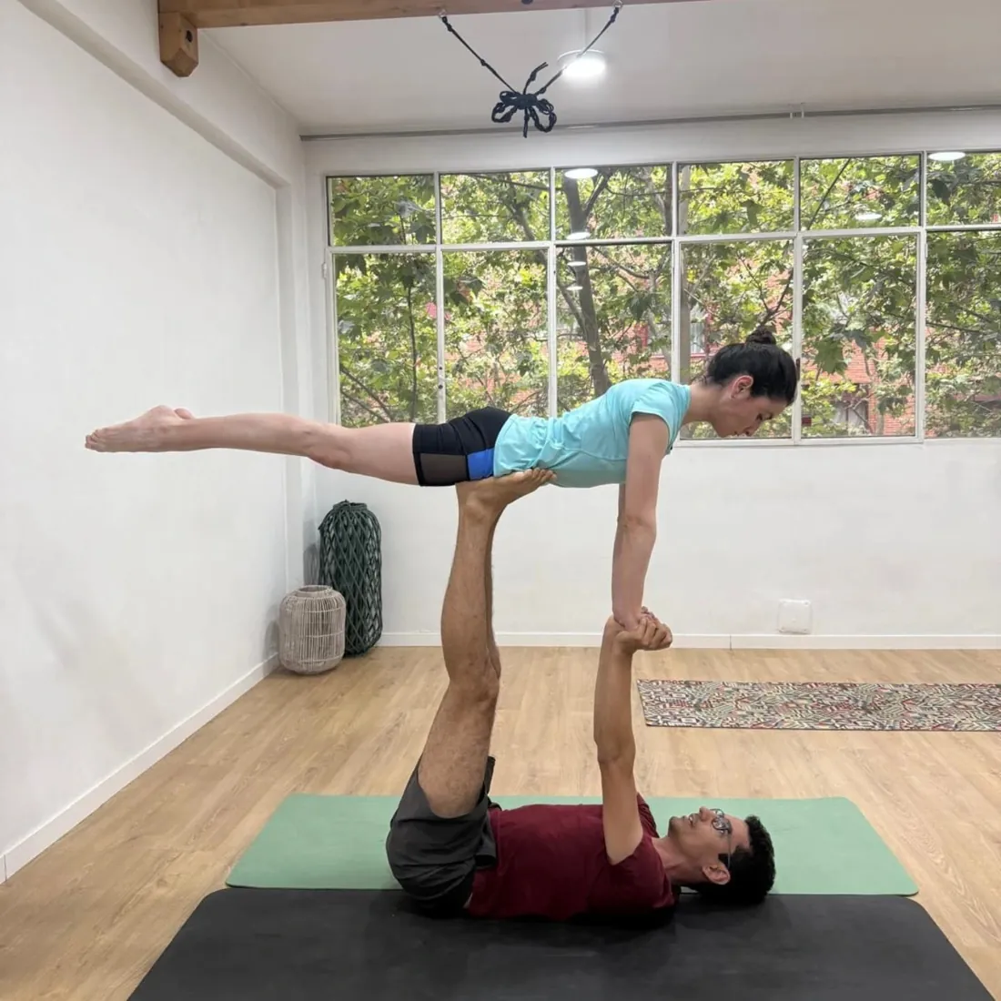 Ernesto Hoyos sosteniendo a una alumna en una postura de acroyoga durante una clase de conciencia corporal